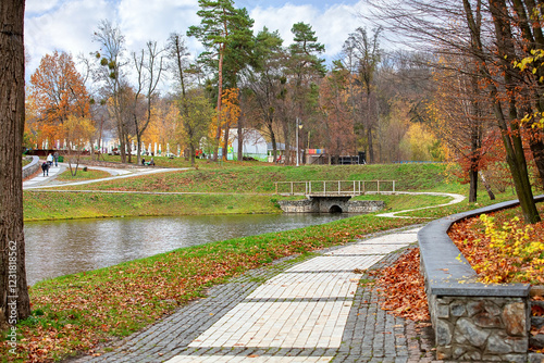 Obraz na płótnie Vibrant autumn stroll along the tranquil pond in a picturesque park setting w salonie