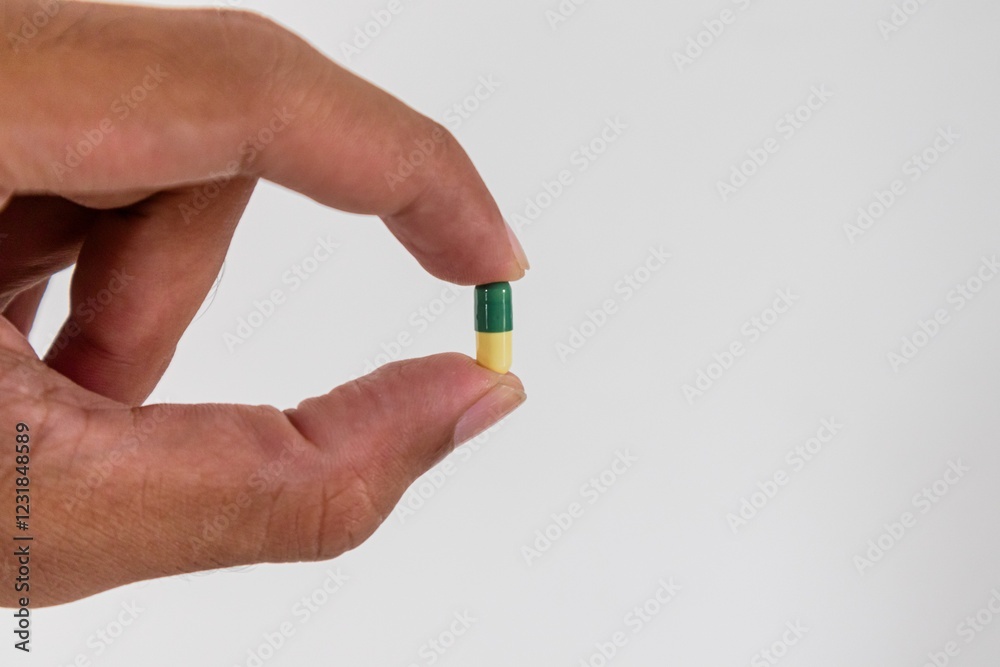 A man's hand holding a pill capsule medicine on a white background A man's hand holding a pill capsule medicine on a white background