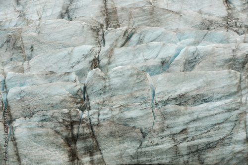 Détail d’un glacier en Islande, révélant les nuances bleutées de la glace et les strates sombres de sédiments. Texture unique et formation naturelle sculptée par le temps et les éléments.