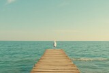 Seagull walking along a wooden pier over calm ocean water during a peaceful afternoon