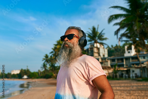 Obraz na plátně Grey-bearded senior man enjoying music on tropical beach