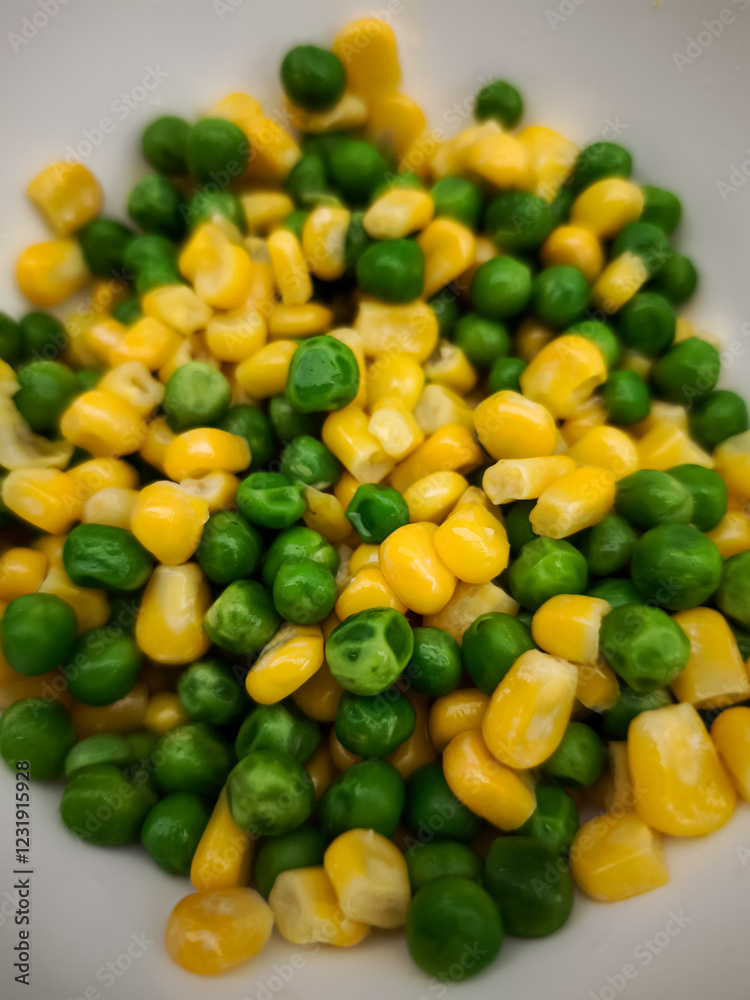 Green and yellow peas and corn kernels mixing together in pristine white ceramic bowl, highlighting fresh vegetable medley Green and yellow peas and corn kernels mixing together in pristine white ceramic bowl, highlighting fresh vegetable medley