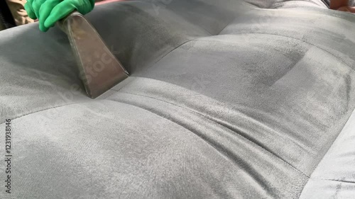 The process of cleaning sofa using extractor to refresh and clean from dust and stains upholstered furniture. Cleaner is dry-cleaning sofa using extractor machine with detergent