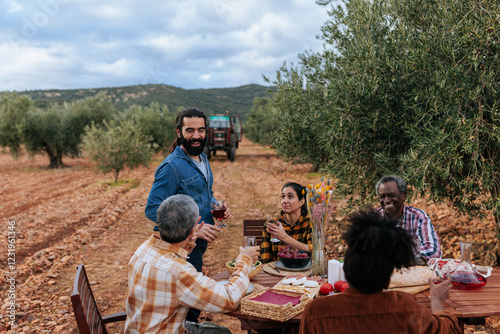 Farmers celebrating harvest with wine and food in olive grove