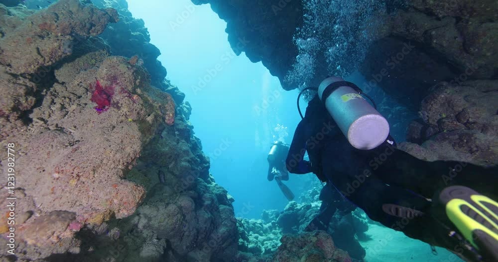 Group of divers swimming in an underwater cave canyon. Diving instructor and group students in underwater exploration. The instructor teaches the students. Scuba diving training and education.