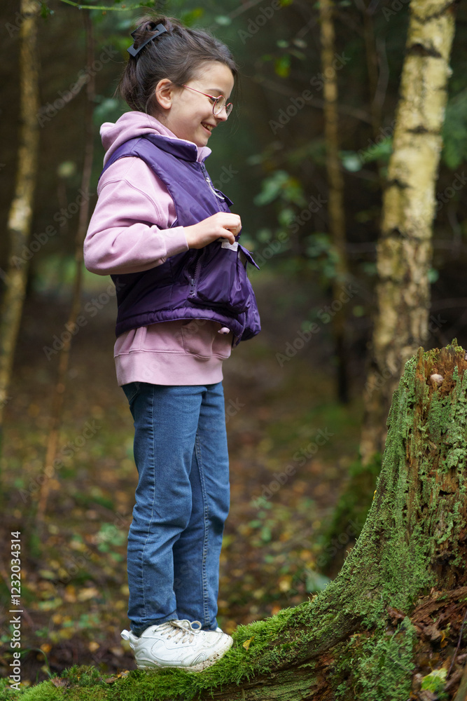 Cute beautiful girl in a vest and glasses smiling during a walk in the middle of a green forest. Concept of children's leisure in nature