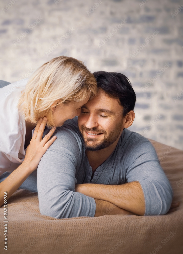 Portrait image - playful hug couple look at each other, lay on home bed, white brick wall background. Blond hair woman, brunette man - love, relationship, happy family, comfortable rest time concept. Portrait image - playful hug couple look at each other, lay on home bed, white brick wall background. Blond hair woman, brunette man - love, relationship, happy family, comfortable rest time concept.