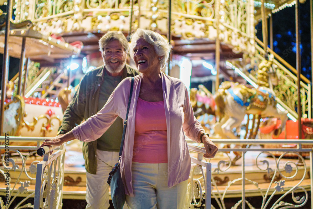 Obraz premium Happy senior couple enjoying carousel ride at night