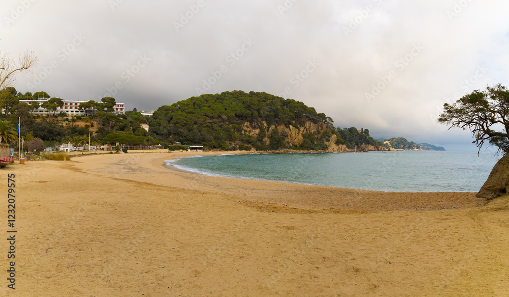 Panorámica de la Playa de Fenals en Catalunya, España, con arena dorada, mar y colinas verdes. Panorámica de la Playa de Fenals en Catalunya, España, con arena dorada, mar y colinas verdes.