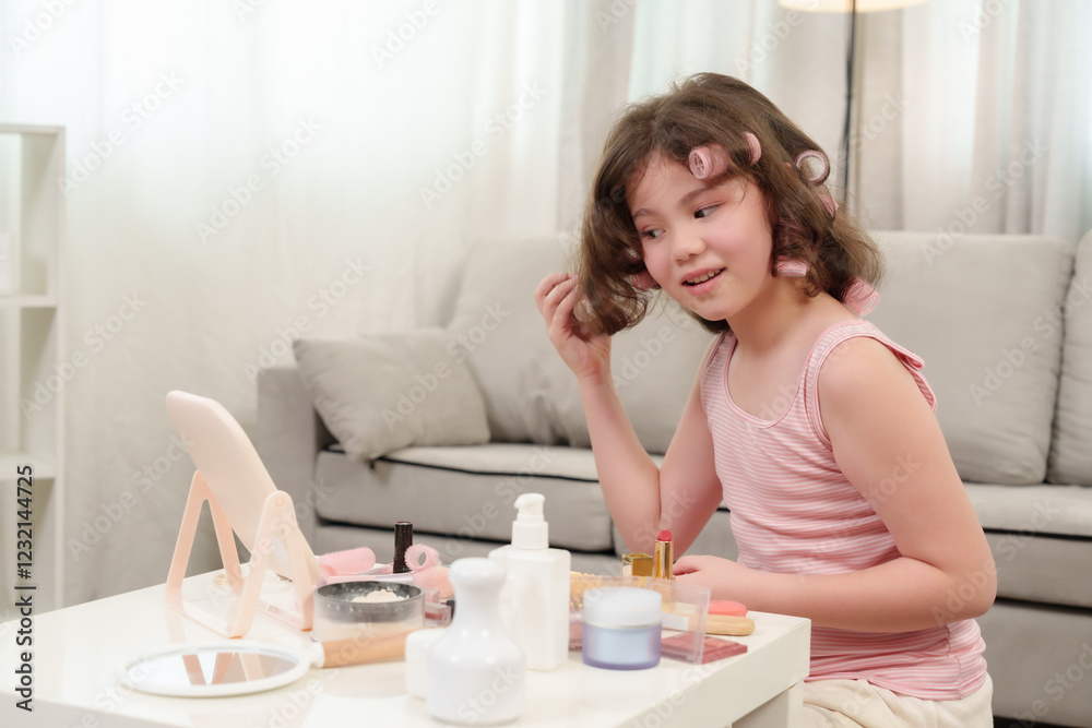 Cute Caucasian girl who loves beauty sitting in living room wearing pink striped tank top with pink hair rollers smiling while styling curly hair using finger beauty products makeup tools mirror table Cute Caucasian girl who loves beauty sitting in living room wearing pink striped tank top with pink hair rollers smiling while styling curly hair using finger beauty products makeup tools mirror table