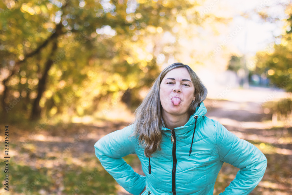 A cheerful woman with blond hair sticks out her tongue as if teasing. A cheerful woman with blond hair sticks out her tongue as if teasing.