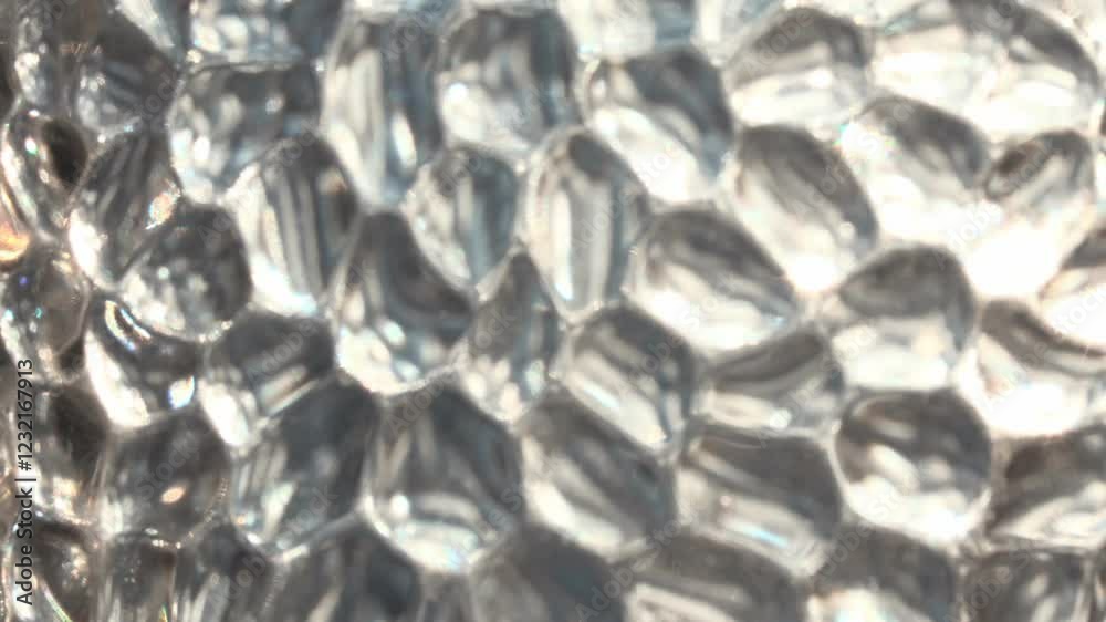 This video features a mesmerizing macro shot of a textured, translucent surface. The intricate patterns and irregular shapes create a visually captivating abstract composition.