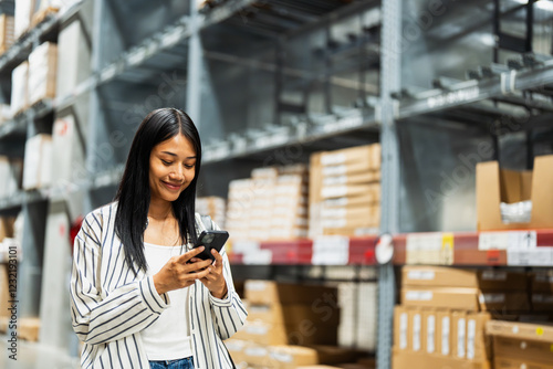 Photos Young Asian woman using smartphone in a warehouse store