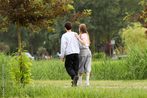 A young guy and his girlfriend are walking in the park along the lake shore. A walk of lovers in the fresh air on a day off. Family leisure in nature