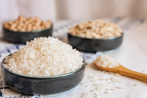 A bowl of white rice in focus with oats and chickpeas blurred in the background, showcasing a clean and rustic food arrangement photo