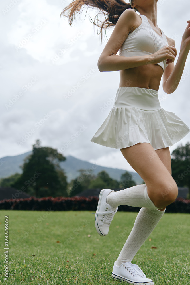 Fit young woman in sporty attire jogging in a green field, showcasing a healthy lifestyle with an active and energetic vibe Fit young woman in sporty attire jogging in a green field, showcasing a healthy lifestyle with an active and energetic vibe