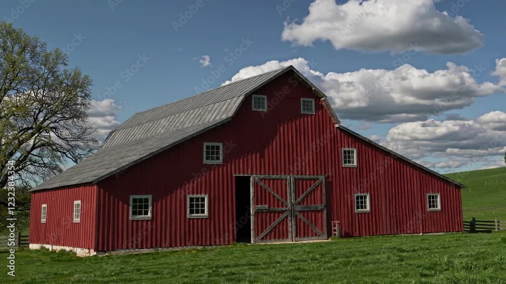 Rustic red barn in a pastoral landscape with vibrant green fields and fluffy clouds in a clear blue sky Rustic red barn in a pastoral landscape with vibrant green fields and fluffy clouds in a clear blue sky