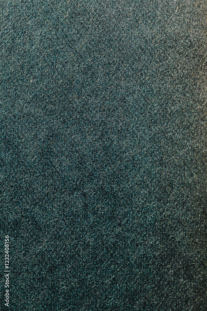 Fototapeta premium Close-up of deep green textured fabric with a dense, short pile for a soft, velvety look. Subtle light variations add gentle depth