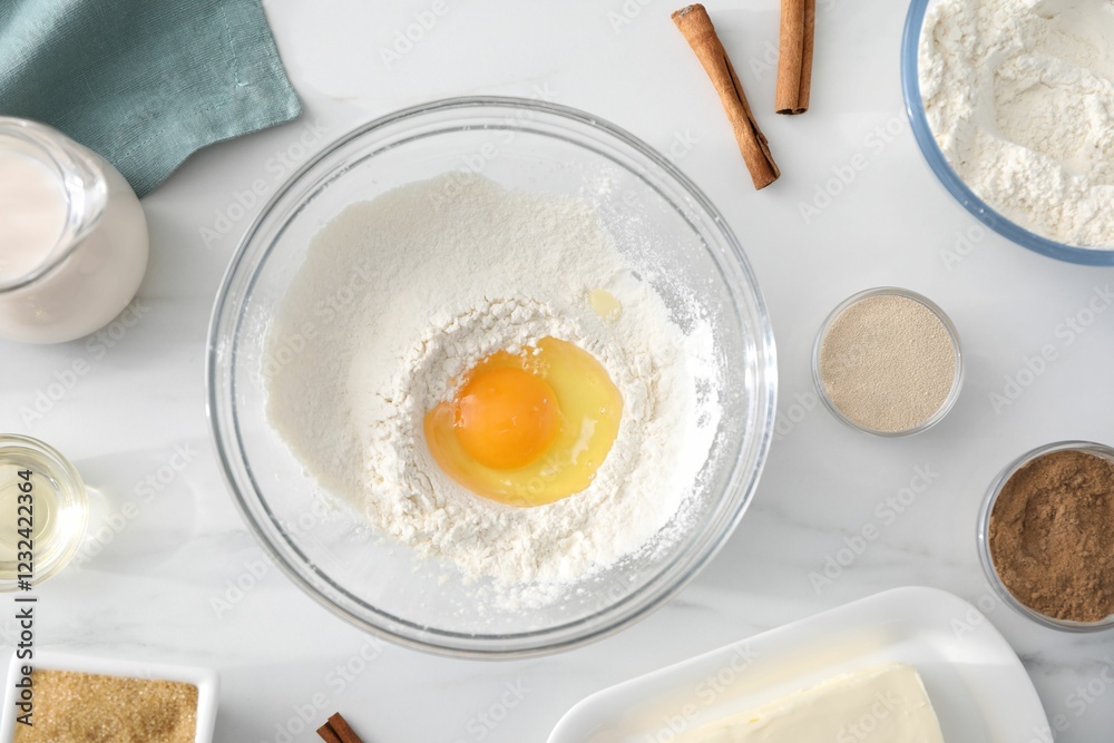 Making cinnamon rolls. Different ingredients for dough on white marble table, flat lay Making cinnamon rolls. Different ingredients for dough on white marble table, flat lay