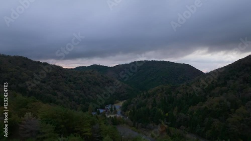 Dawn light and low clouds over forested valley with foggy mountain landscape