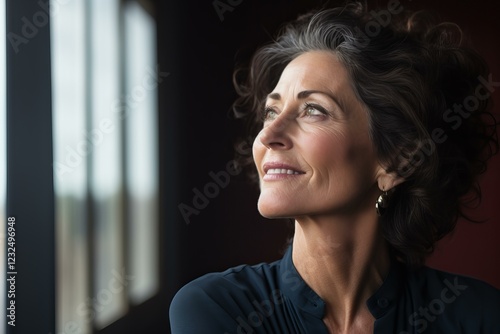 Portrait of a successful mature businesswoman smiling and looking up hopefully in office window light