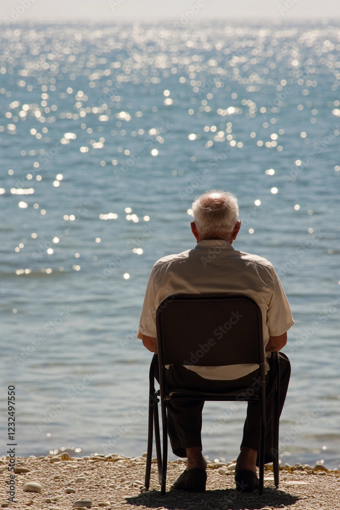 Fototapeta premium Elderly man gazing at tranquil water on a sunny day