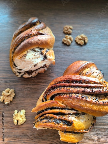 two halves of braided bun with poppy seeds and walnuts on dark wooden background photo