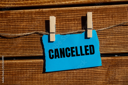 Cancelled message written on ripped blue torn paper piece with wooden background. Conceptual cancelled symbol. Copy space. photo