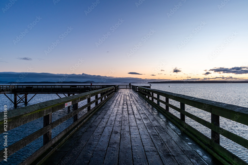 Naklejka premium Scenic Wooden Pier Extending Into the Ocean During Serene Sunset