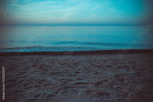 Fototapeta Naklejka Na Ścianę i Meble -  Calm beach on the Baltic Sea in the warm light of sunset. Gentle waves, sandy coastline and subtle atmosphere of relaxation. Perfect image for themes related to nature, travel, and holidays.