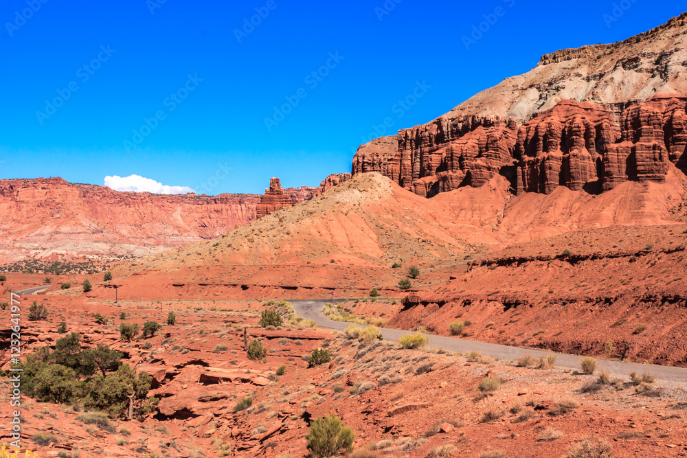 Fototapeta premium A road winds through a desert landscape with a blue sky overhead