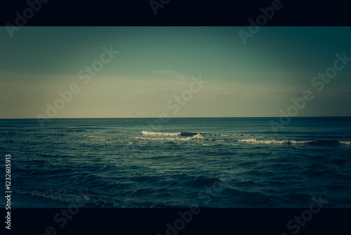 Fototapeta Naklejka Na Ścianę i Meble -  Calm beach on the Baltic Sea in the warm light of sunset. Gentle waves, sandy coastline and subtle atmosphere of relaxation. Perfect image for themes related to nature, travel, and holidays.