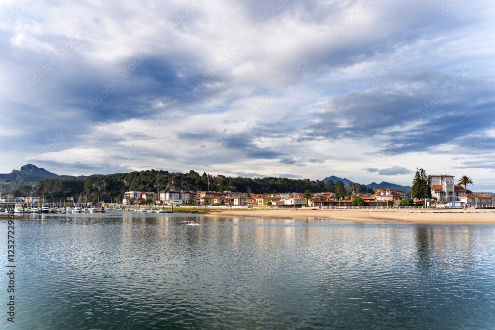 Naklejka premium Ribadesella cityscape reflecting on the calm water of the sella river in asturias, spain