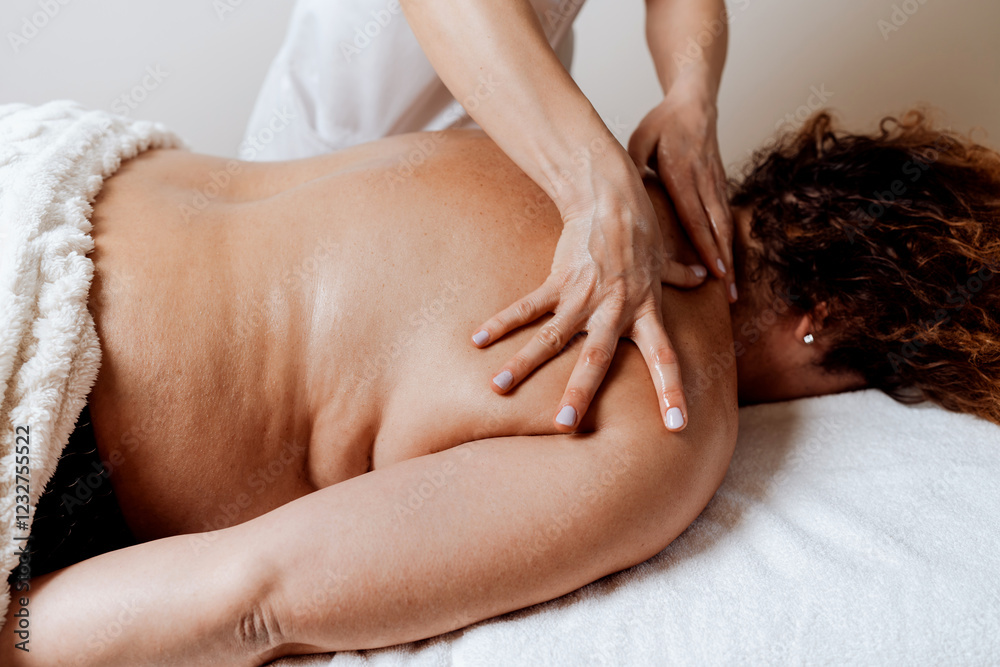 Fototapeta premium Obese middle-aged woman receives a special body massage intended for weight reduction and correction of bad posture. Modern weight loss physical therapy and beauty spa concept.