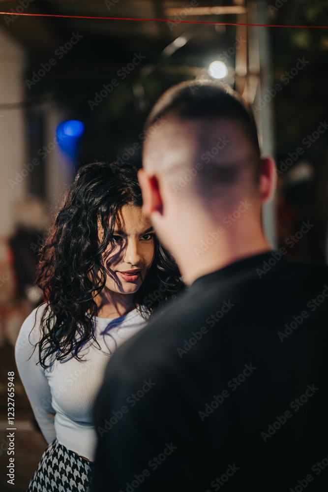 A young woman with curly hair is making intense eye contact with someone in a moody nighttime setting, evoking curiosity and emotion. A young woman with curly hair is making intense eye contact with someone in a moody nighttime setting, evoking curiosity and emotion.