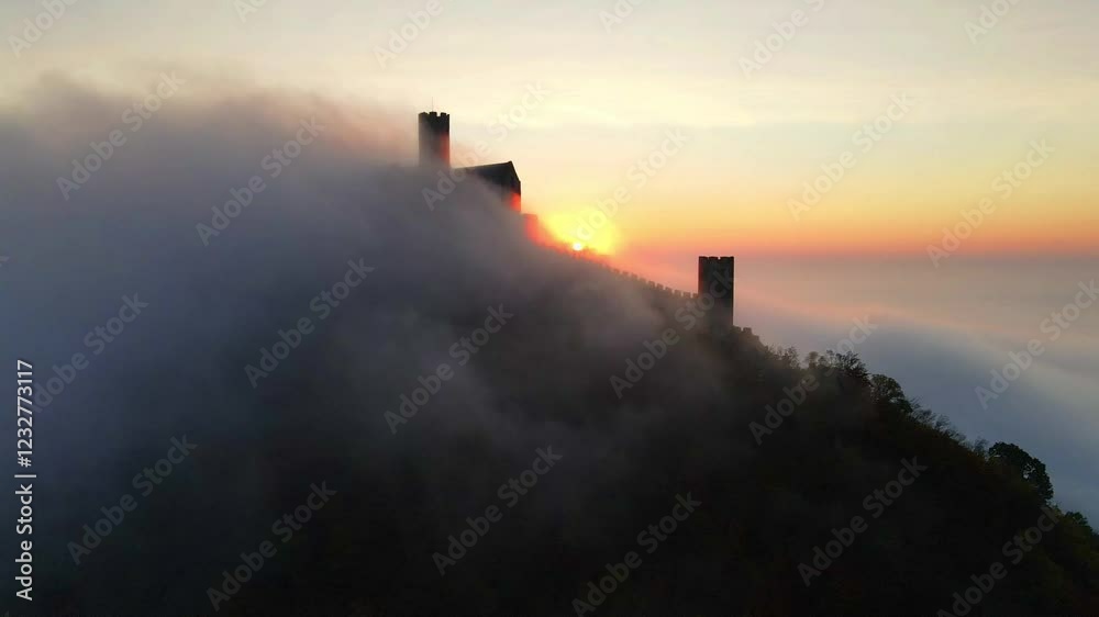 Fairytale sunrise over a castle shrouded in clouds, view from above