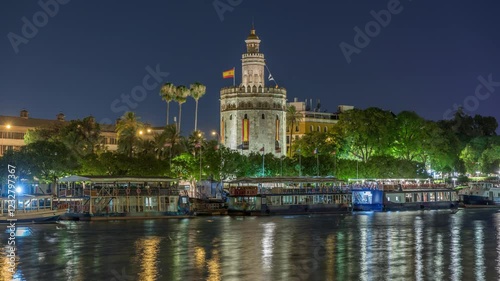 Torre del Oro timelapse hyperlapse, a dodecagonal military watchtower in Seville, Spain. Built by the Almohads to control Guadalquivir River access. Historic landmark with reflections at night. photo