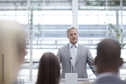 Podium, office and business man with audience for presentation, conference and convention. Corporate, professional speaker and person by stand for management seminar, tradeshow and workshop event