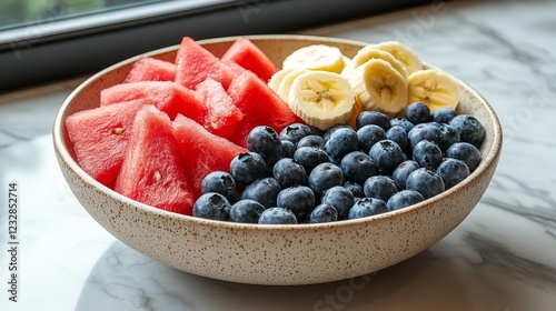 Colorful fruit bowl with bananas, blueberries, and watermelon on a dark surface