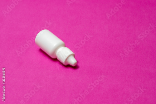 A white bottle, a vial for eye and nasal drops on a red background.