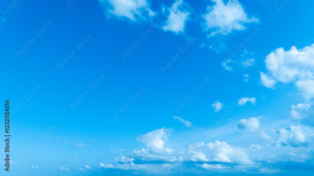 A bright blue sky with delicate white clouds floating, evoking a peaceful and refreshing summer feeling. A bright blue sky with delicate white clouds floating, evoking a peaceful and refreshing summer feeling.