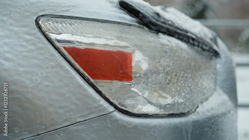 Detailed close-up of a car's frosted taillight covered with ice and snow, highlighting intricate ice patterns and the chilling effect on vehicle surfaces during winter photo