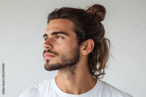 Profile of young man with long brown hair tied in a bun