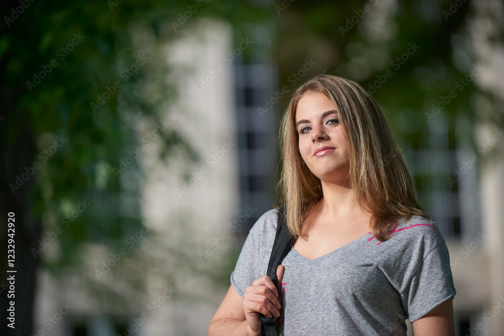 Attractive female college student on campus in t-shirt - holding backpack Attractive female college student on campus in t-shirt - holding backpack