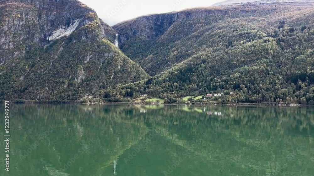 Mountains and waterfall are reflecting on a perfectly still lake in norway