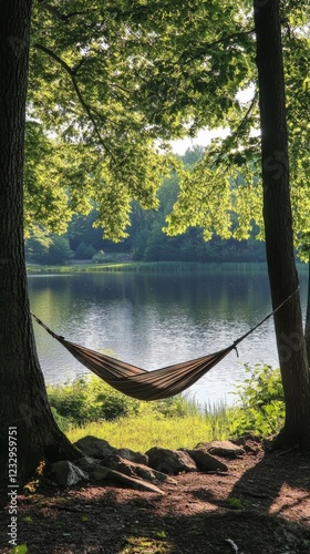 Relaxing hammock between trees by a calm lake surrounded by lush greenery on ...