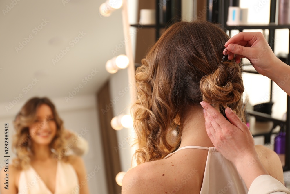 Naklejka premium Stylist working with client in salon, making hairstyle