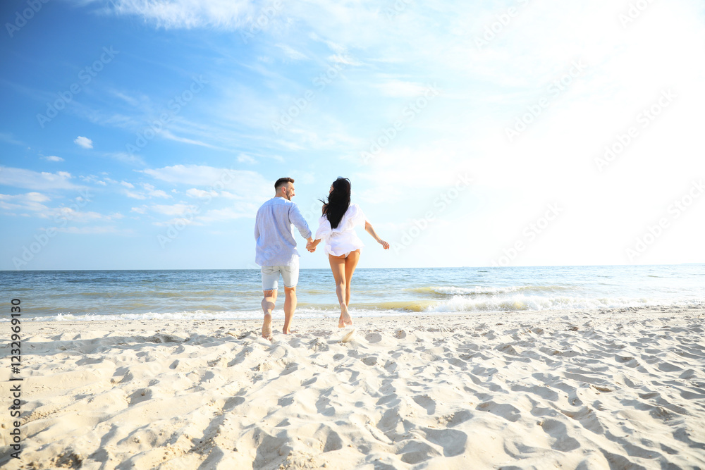 Happy couple running together on beach, back view Happy couple running together on beach, back view