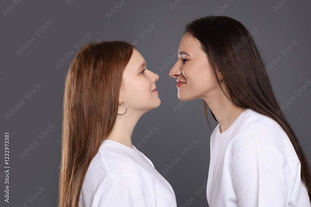 Portrait of beautiful mother with teenage daughter on grey background Portrait of beautiful mother with teenage daughter on grey background