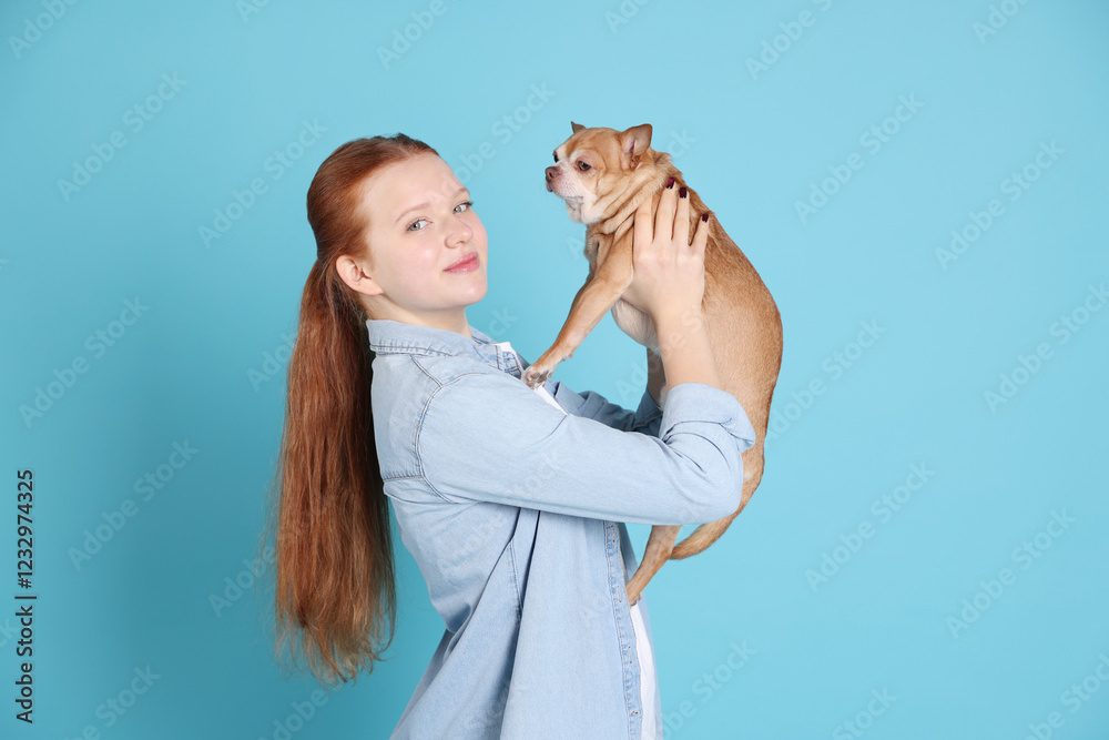 Teenage girl with her cute Chihuahua dog on light blue background Teenage girl with her cute Chihuahua dog on light blue background